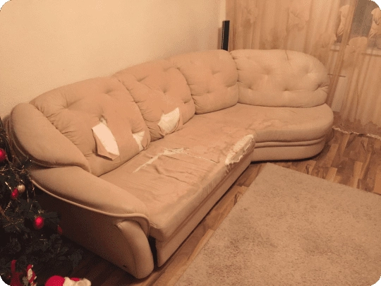 Damaged beige leather sofa with torn seat cushions before restoration service in New York