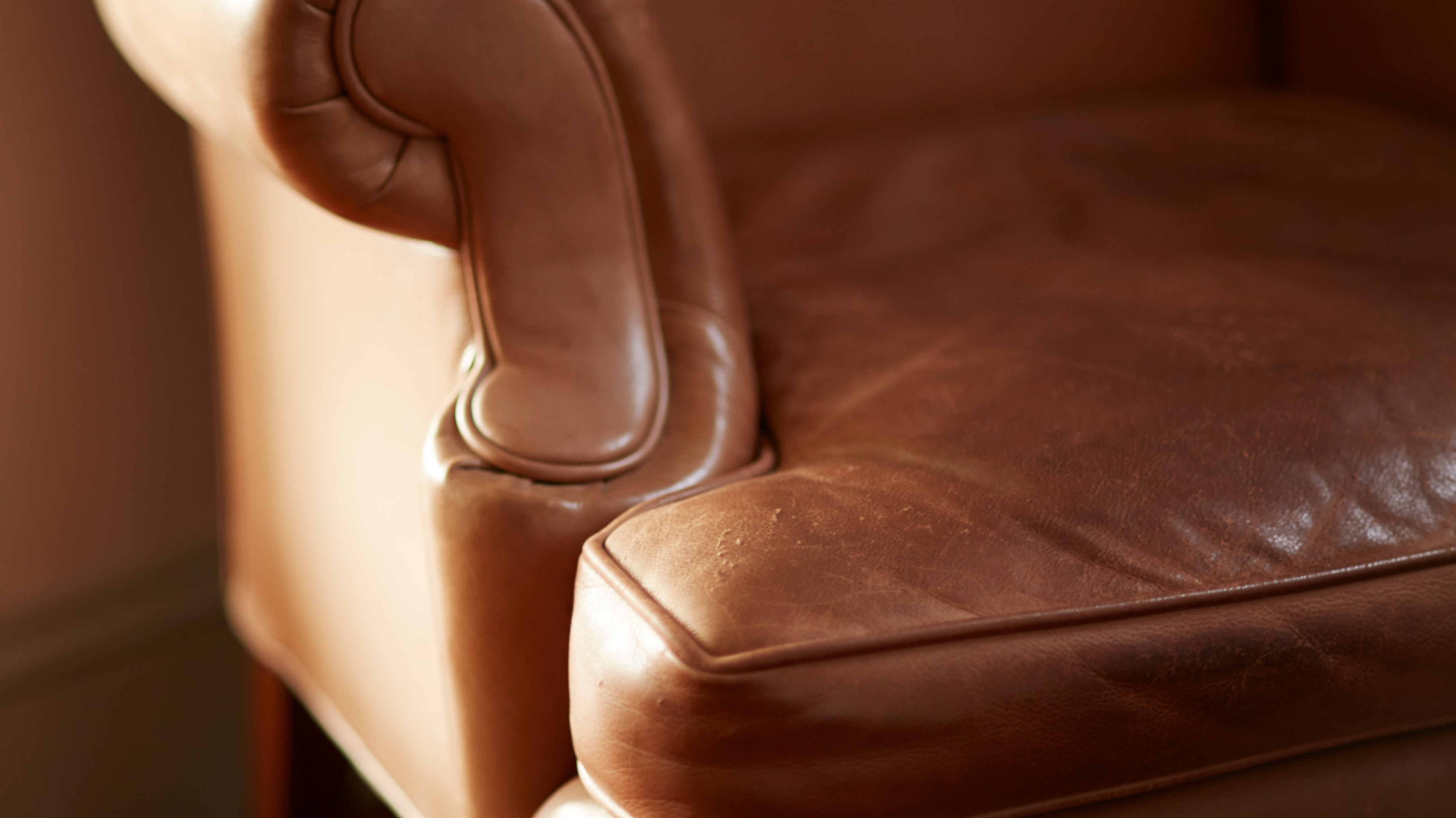 Close-up of restored brown leather armchair seat and armrest