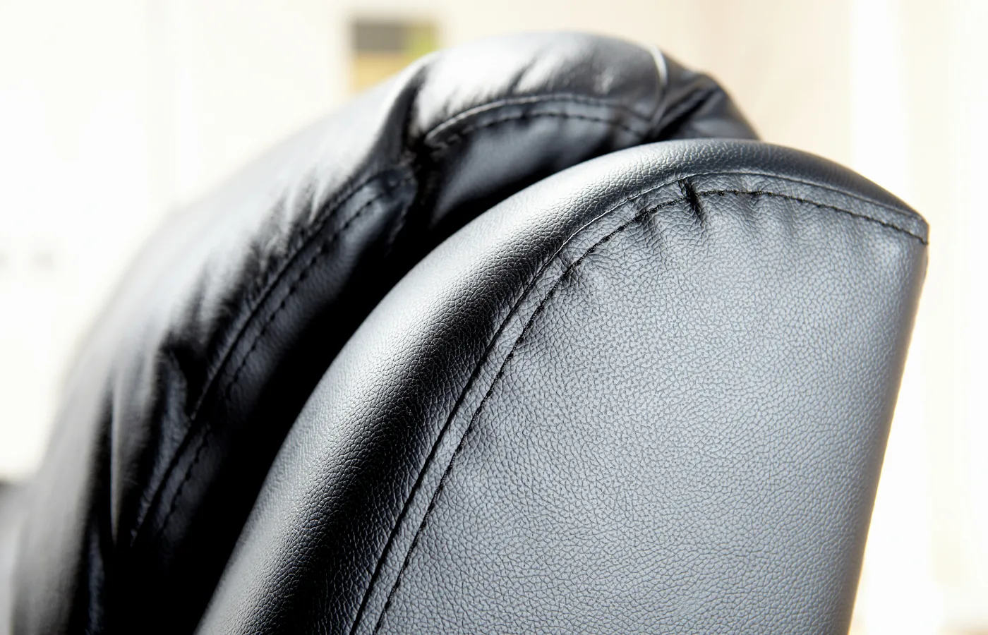 Rolled arm and seat of a finished black leather sofa, a custom cushions near me job completed in Brooklyn