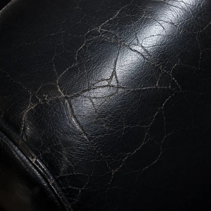 Web of fine cracks across the surface of a black leather seat