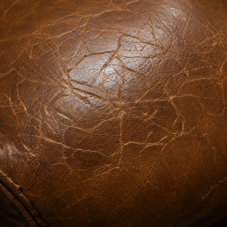 Tan bar stool leather covered in a dense web of fine scratches and scuffing