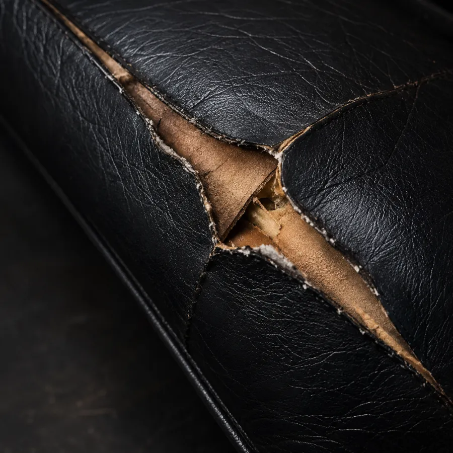 Star-shaped tear opening in a black leather seat cushion