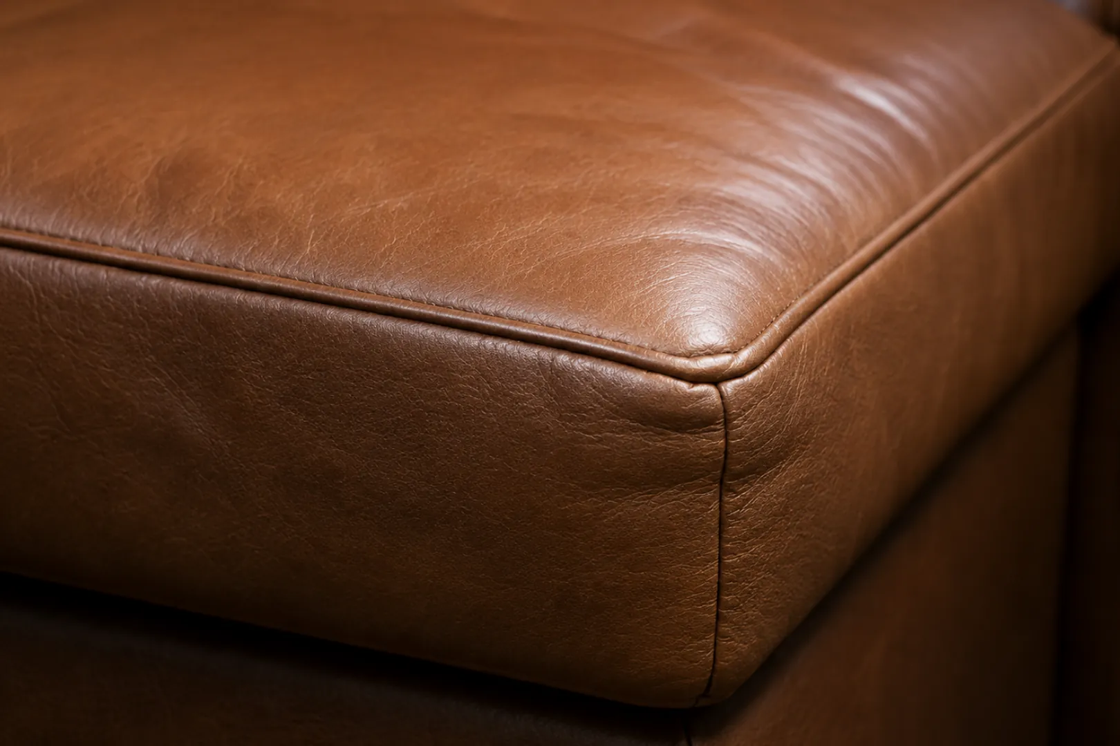 Corner of a brown leather seat cushion showing how the hide folds at the edge