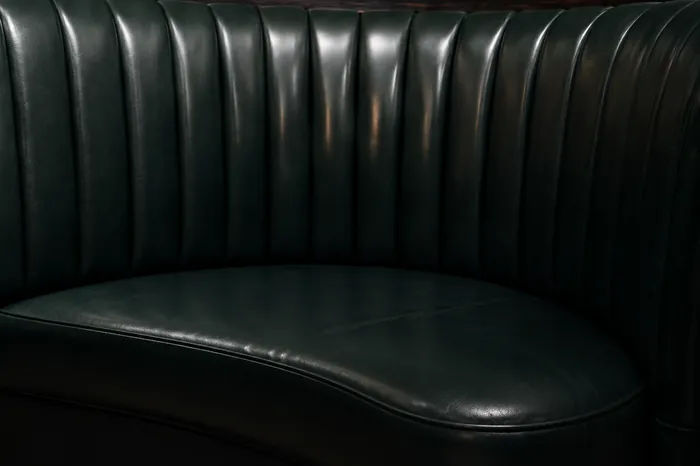 Channel-tufted leather banquette back rebuilt with new material