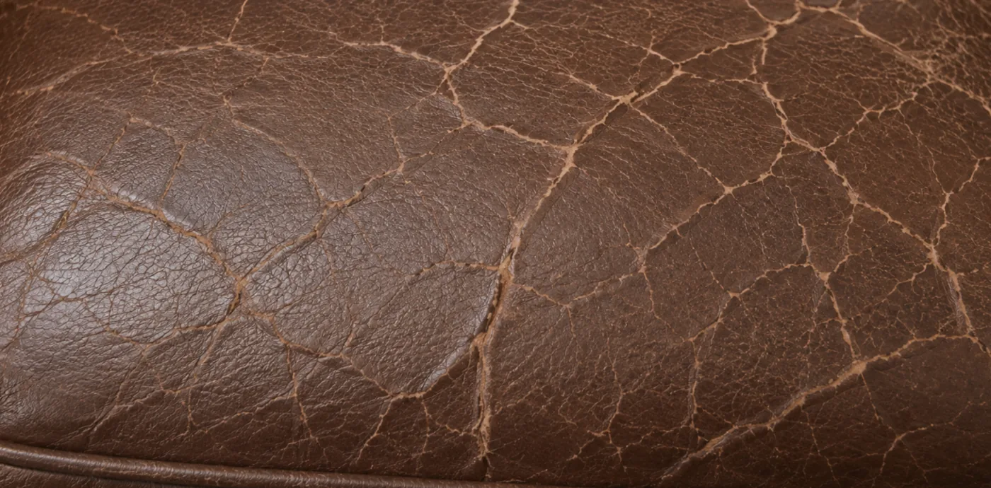 A web of cracks opening across the topcoat of brown corrected grain leather