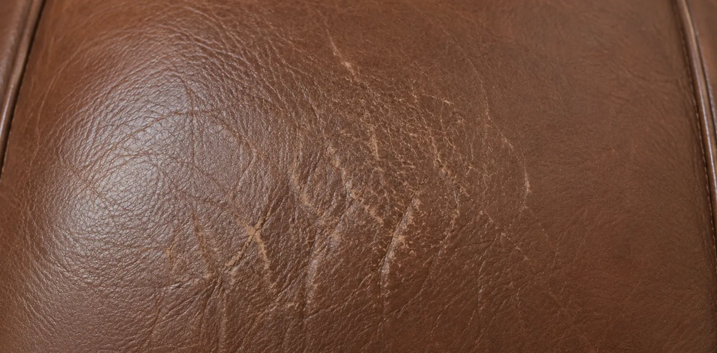 Corrected grain leather faded unevenly, the original shade surviving only at the edges