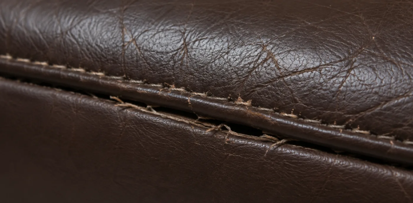 A seam on corrected grain leather where the stitching has broken and the panels have parted