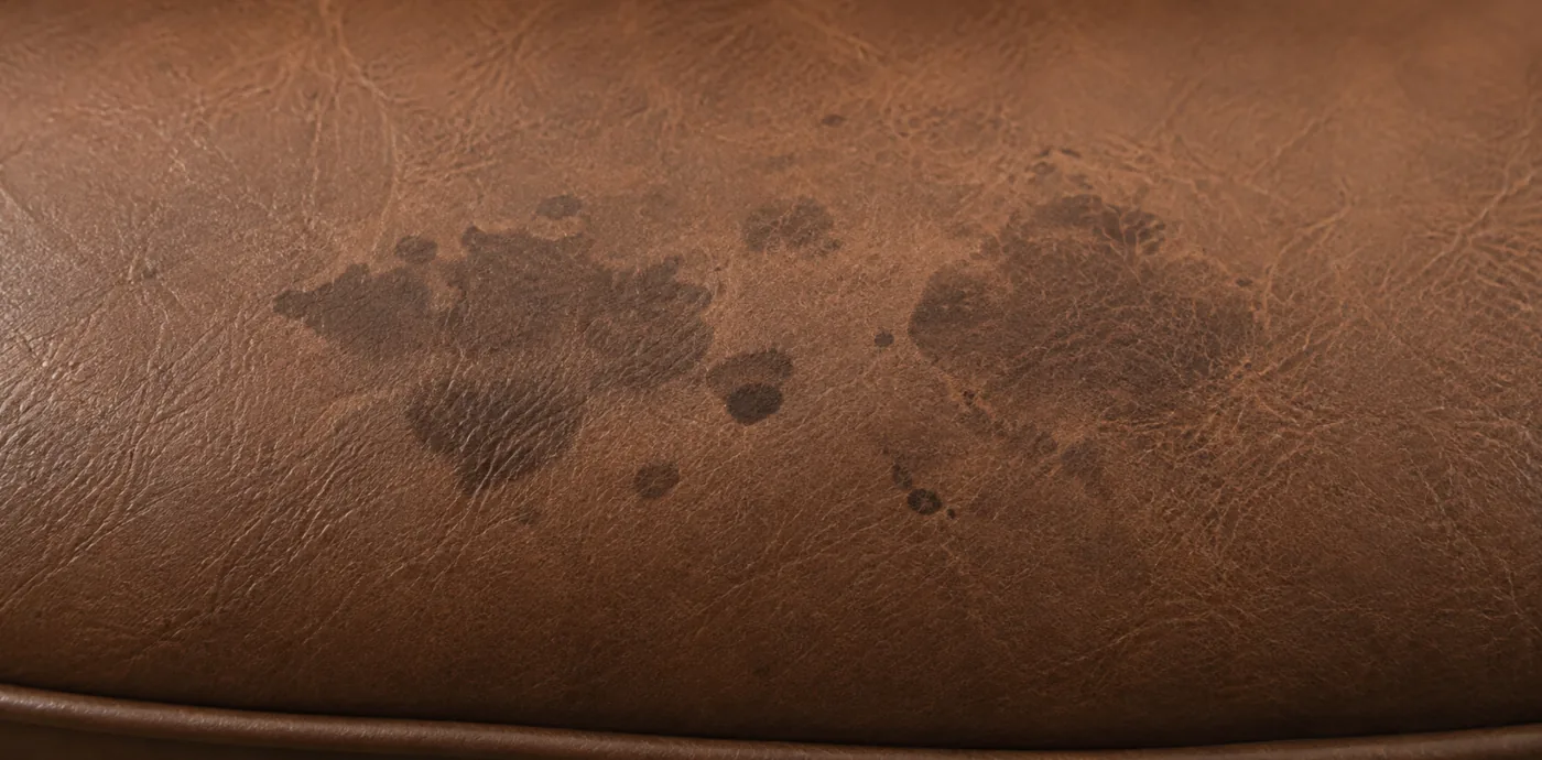 Dark blotchy staining sitting on the coated surface of tan corrected grain leather