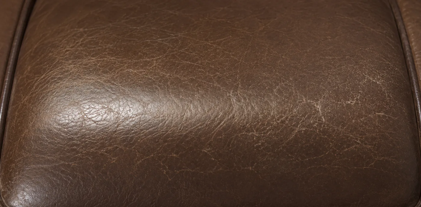 A polished, crazed patch where repeated contact has burnished the coating on corrected grain leather