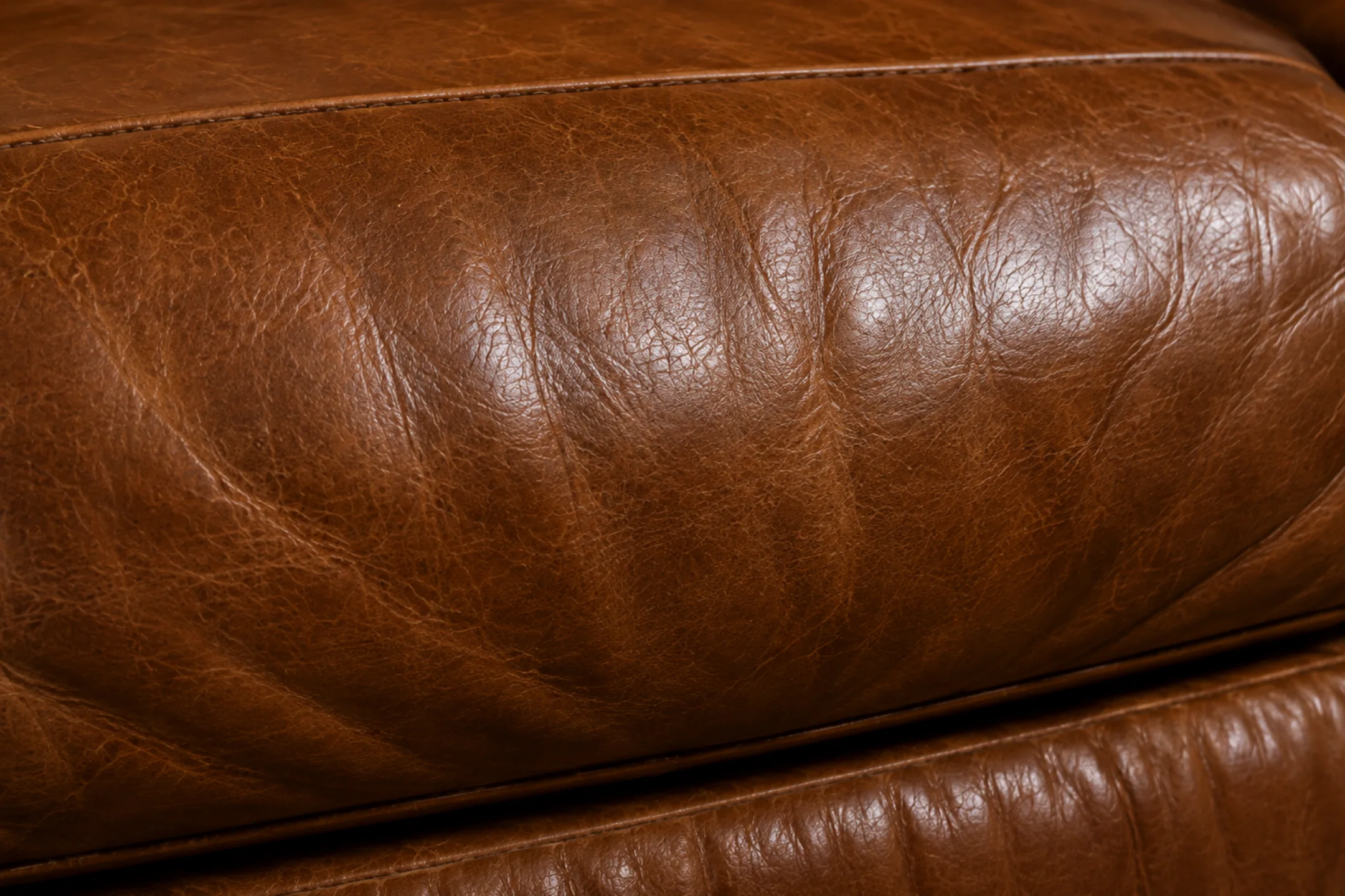 Close-up of an untouched semi-aniline leather panel holding an even factory satin finish with no wear