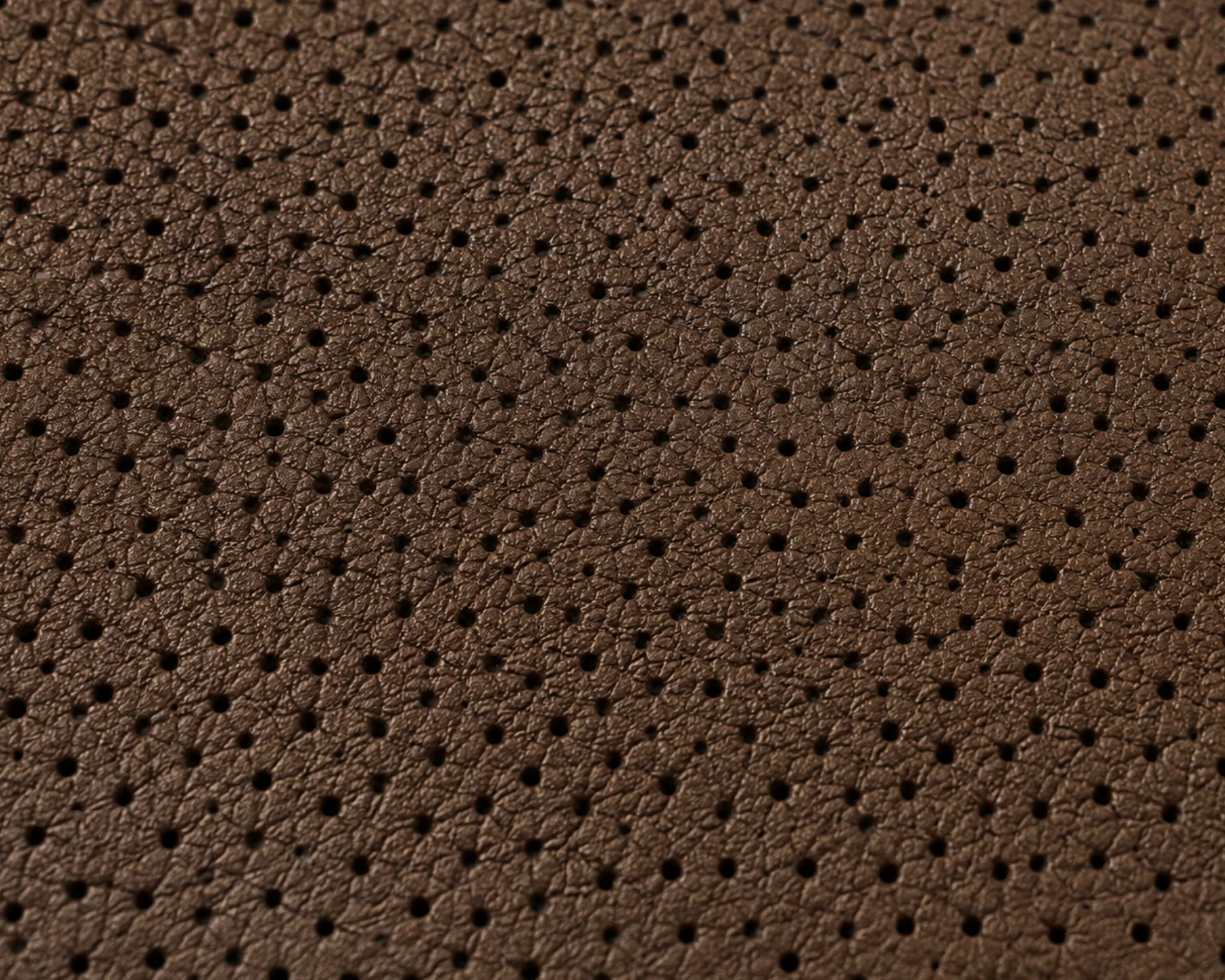 Perfectly uniform perforations across brown faux leather, with none of the irregularity of hide