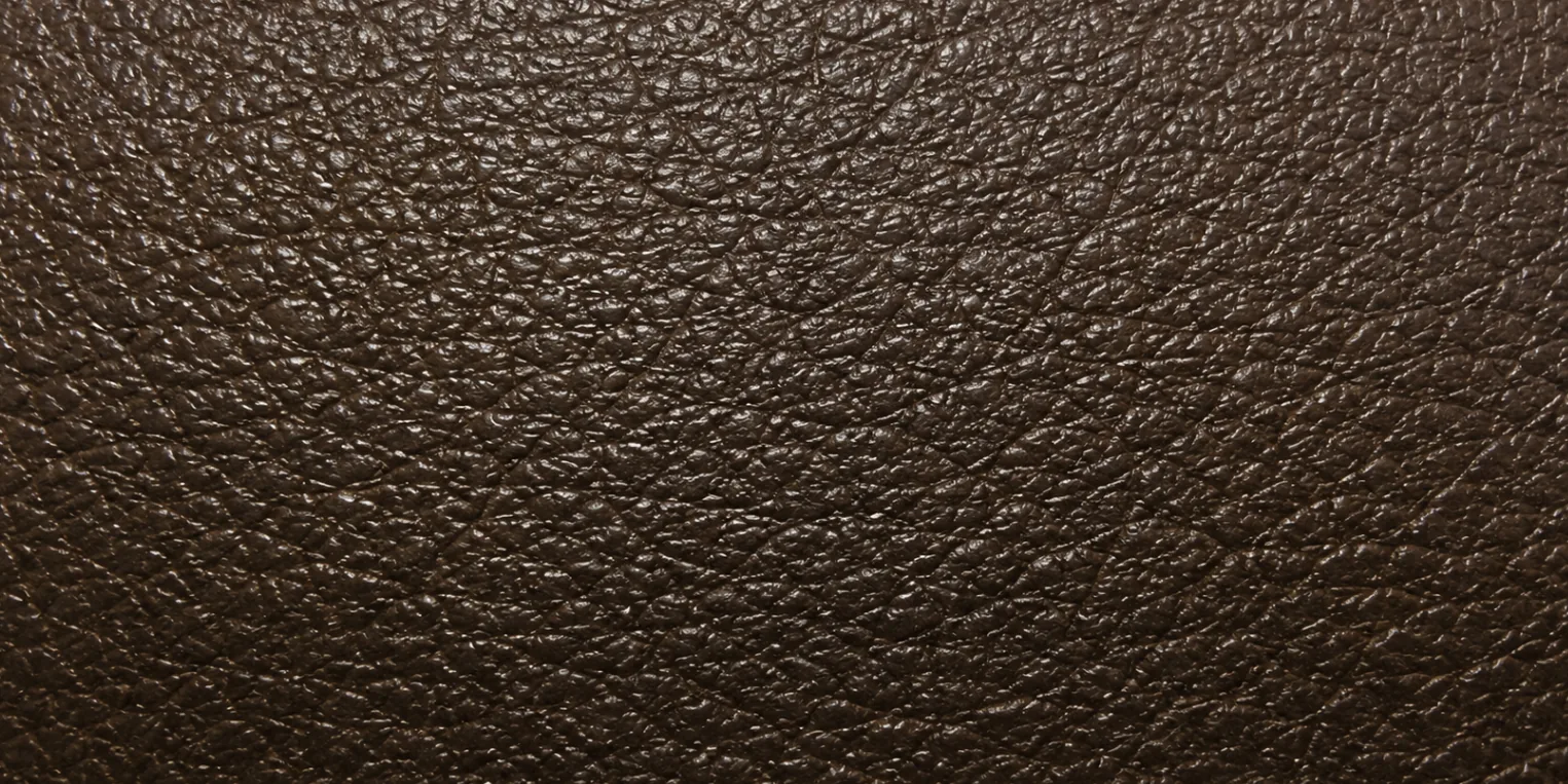 An unbroken dark brown faux leather surface with the dull, slightly wet-looking sheen of a degrading polymer