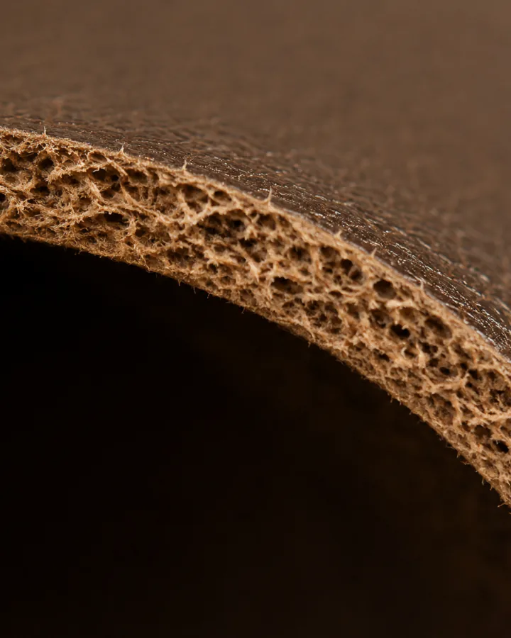 The cut edge of a full grain hide, the fibre continuous through the thickness and tightest at the top face.