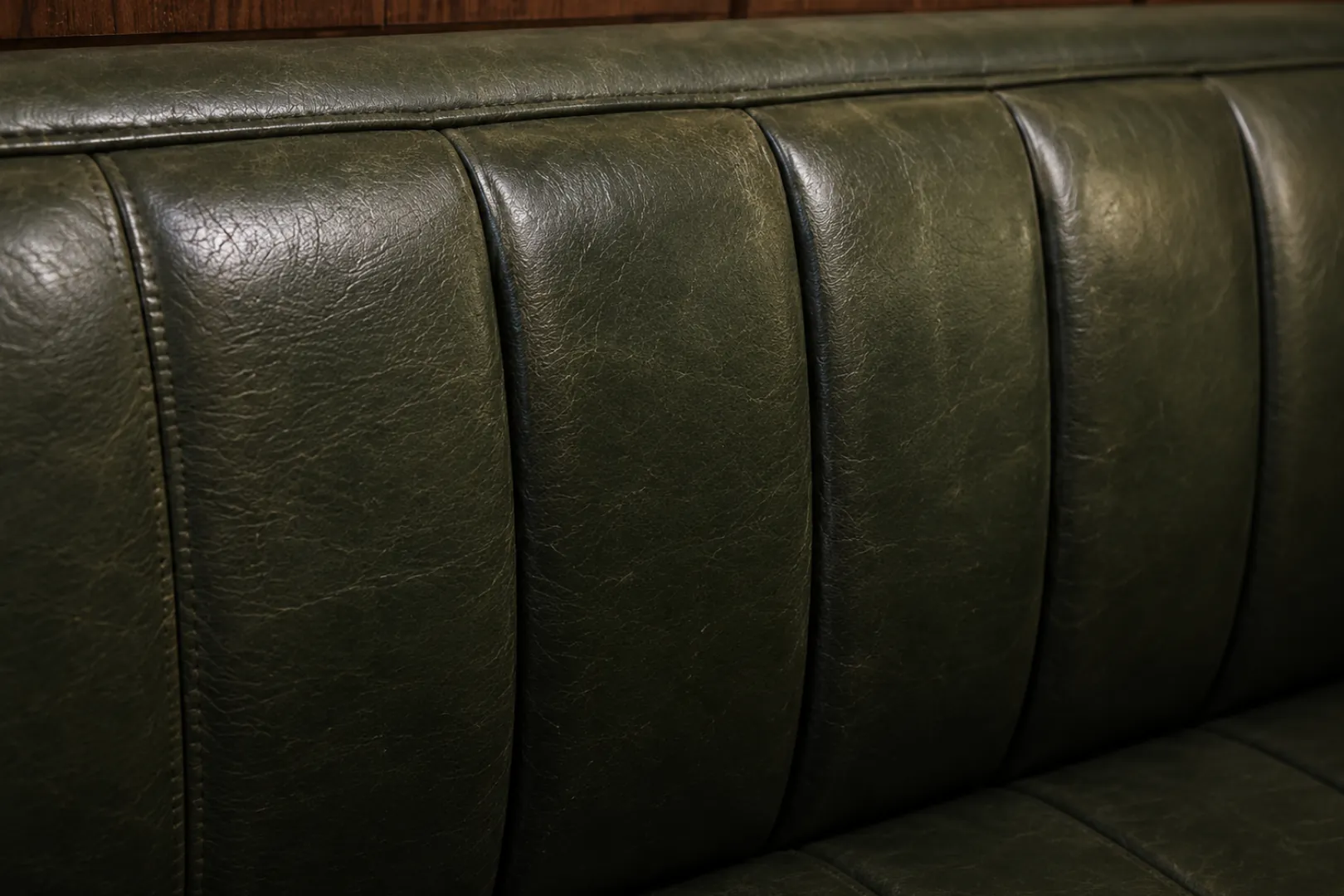 Green channelled leather banquette showing the sheen of its finish under room light