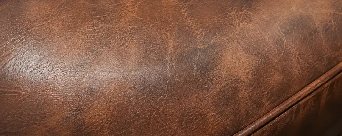 Mottled two-tone brown leather showing uneven color loss across a bar seat