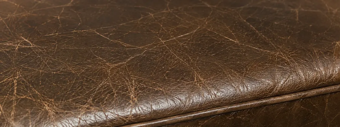 Dense cracking across the front edge of a brown leather seat cushion