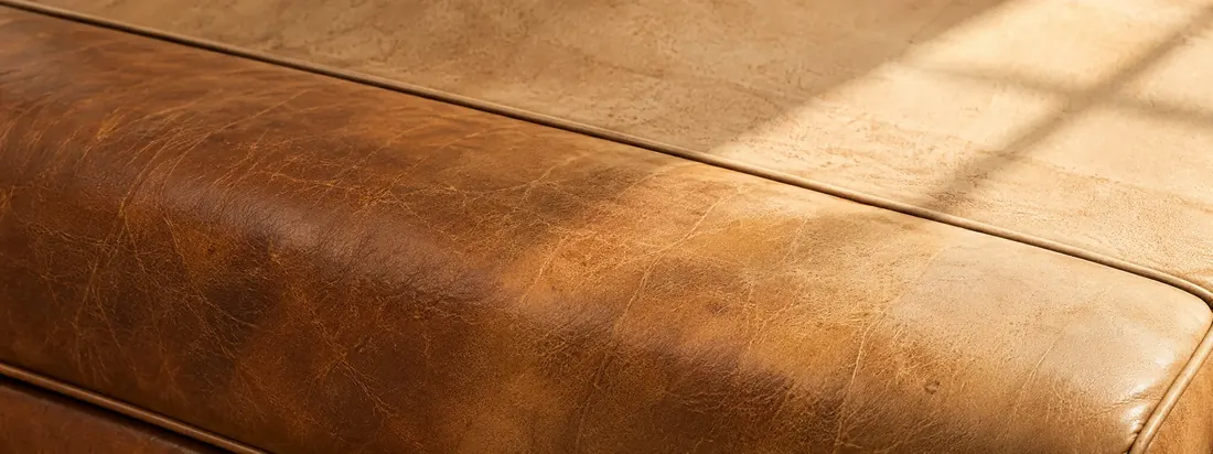 Leather bench crossed by a sunlight line, deep color in shade and pale where the light falls
