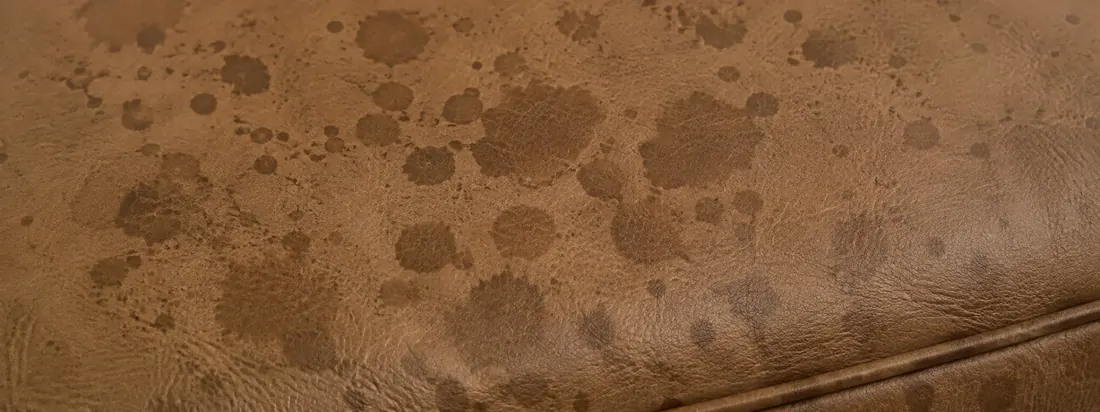 Tan leather marked with dark water rings and droplet spots