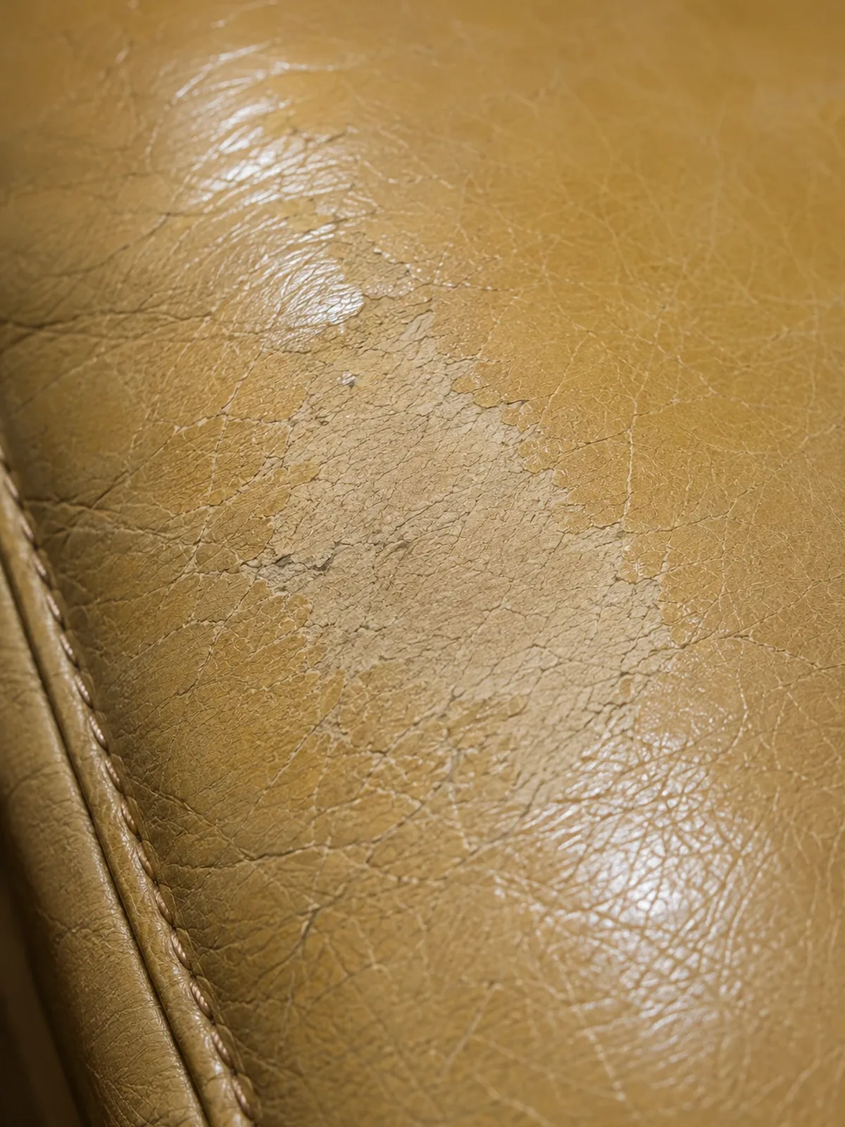 Pale worn patch abraded through the colour on a tan hotel leather chair