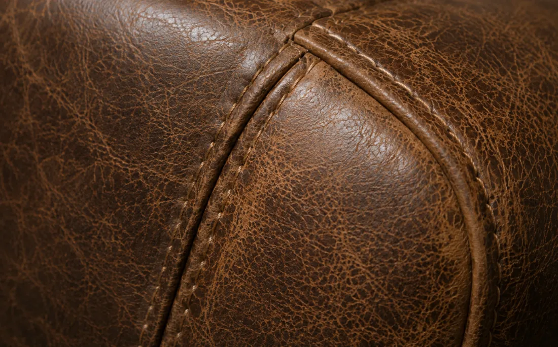 The original leather panel before replacement, cracked and dried out along the stitched seam