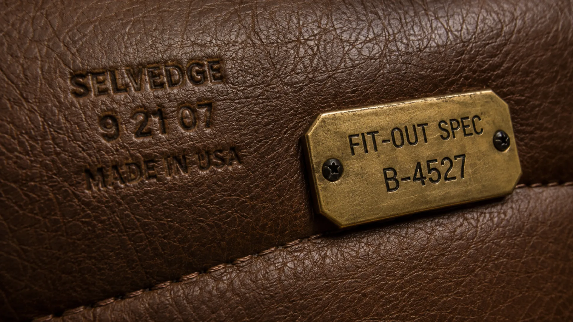 Selvedge stamp and brass fit-out spec tag on an original leather panel