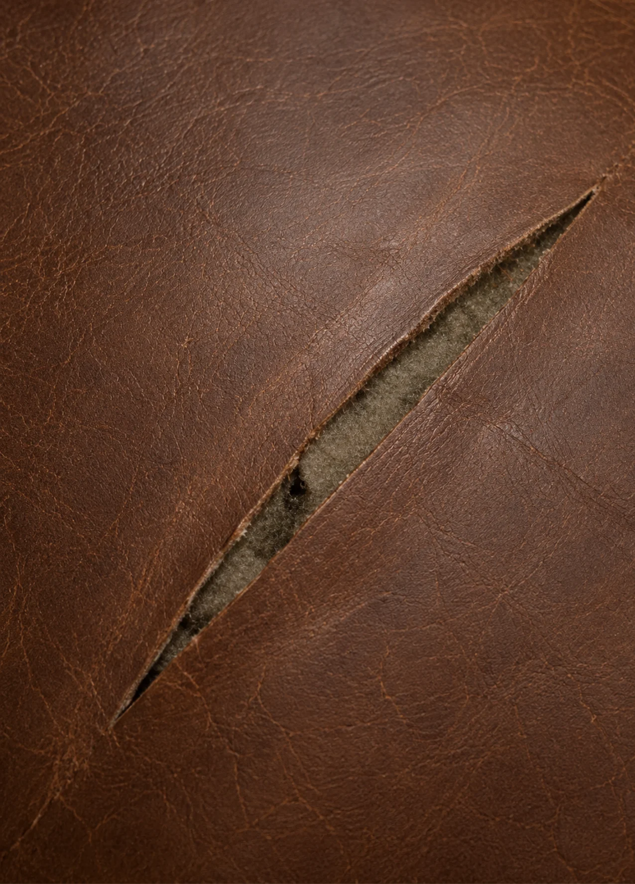 A clean straight cut in tan leather upholstery with the edges still meeting