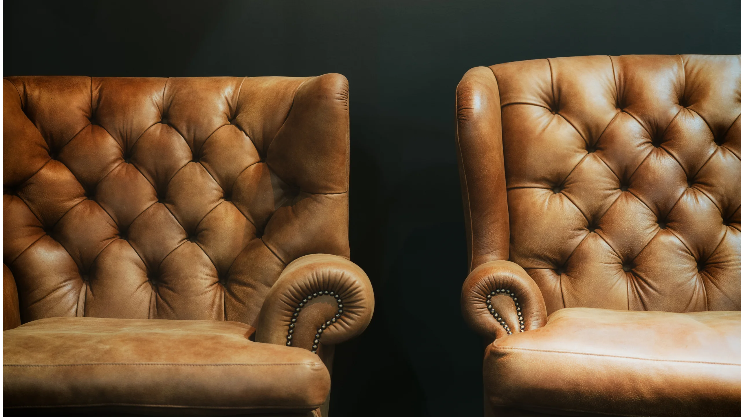 Two tan tufted leather wingback chairs