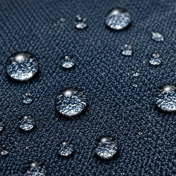 Macro of a navy woven performance fabric, water beading into round droplets that sit on the treated surface without spreading
