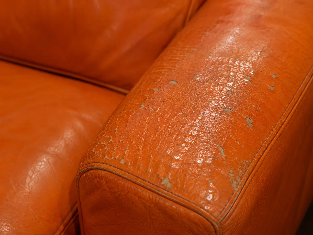Cracked and flaking finish on the arm of an orange leather chair