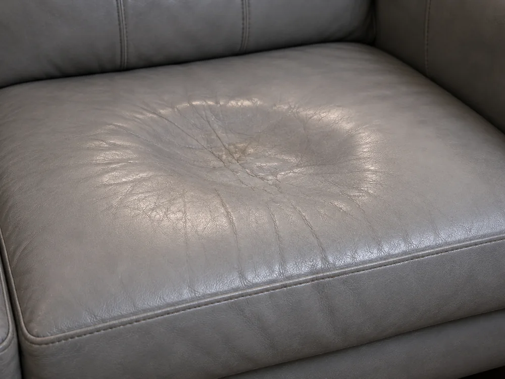 Grey leather seat cushion dished where the foam underneath has bottomed out