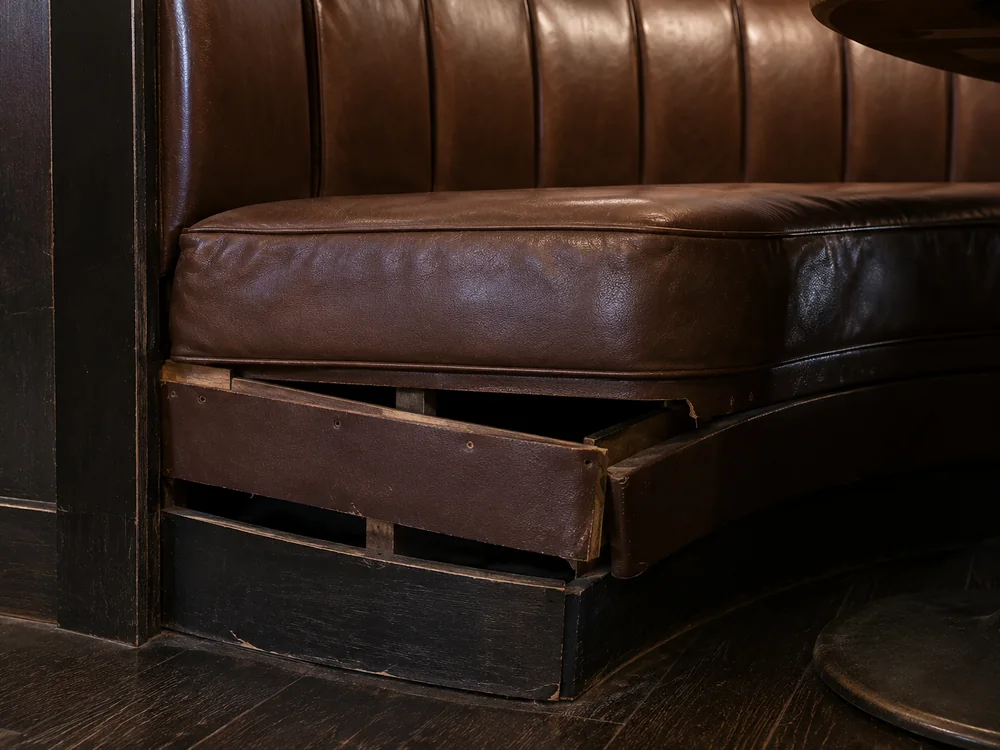 Loose base panel under a brown leather booth exposing the wood platform