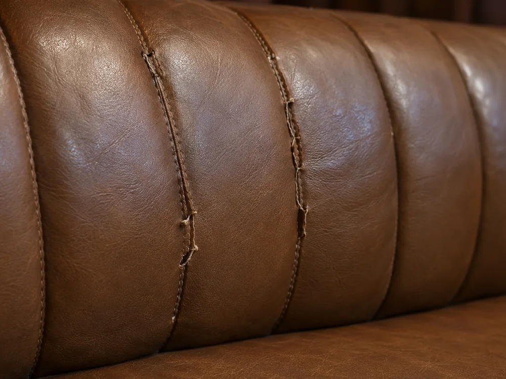 Split stitching between the channels of a brown leather banquette back