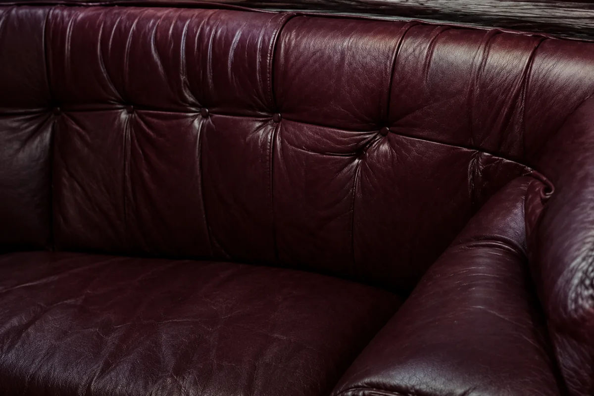 Oxblood tufted club seating with a rolled arm