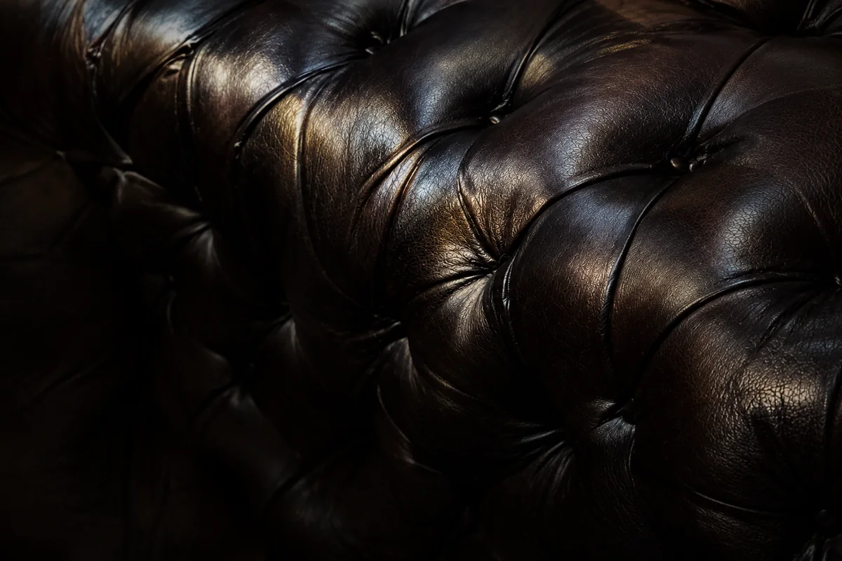 Dark brown button-tufted leather banquette back in a nightclub
