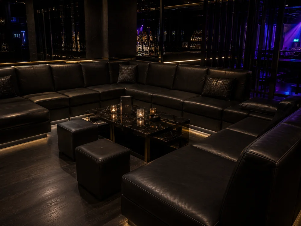 Large U-shaped black leather modular sectional in a nightclub VIP area