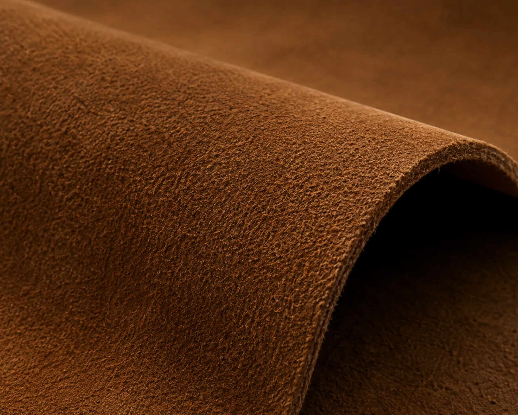 A softly folded panel of nubuck leather, the velvety nap catching the light along the curve