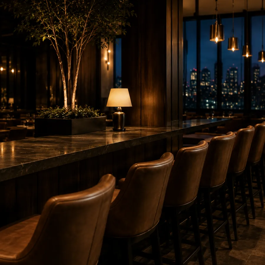 Leather bar stools at a window-side bar overlooking the city at night