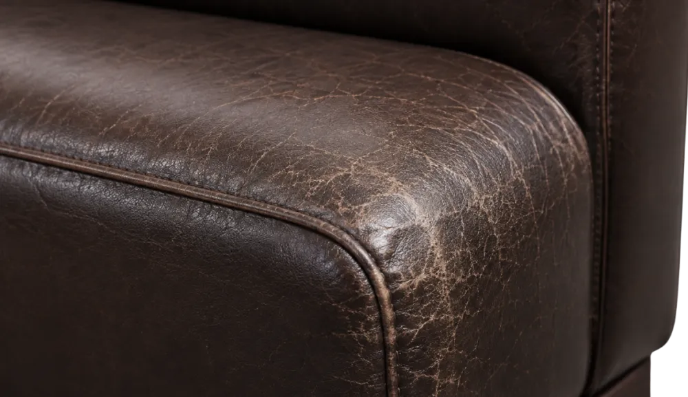 Close-up of a bonded leather armrest corner showing a concentrated band of cracking where hands rest