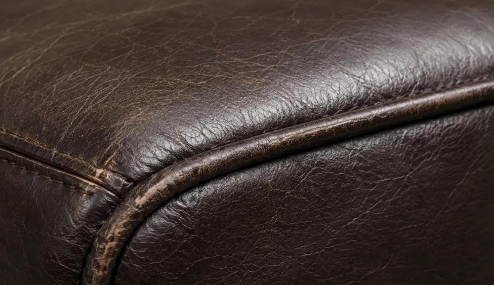 Close-up of bonded leather piping where the raised seam has worn lighter than the panel around it