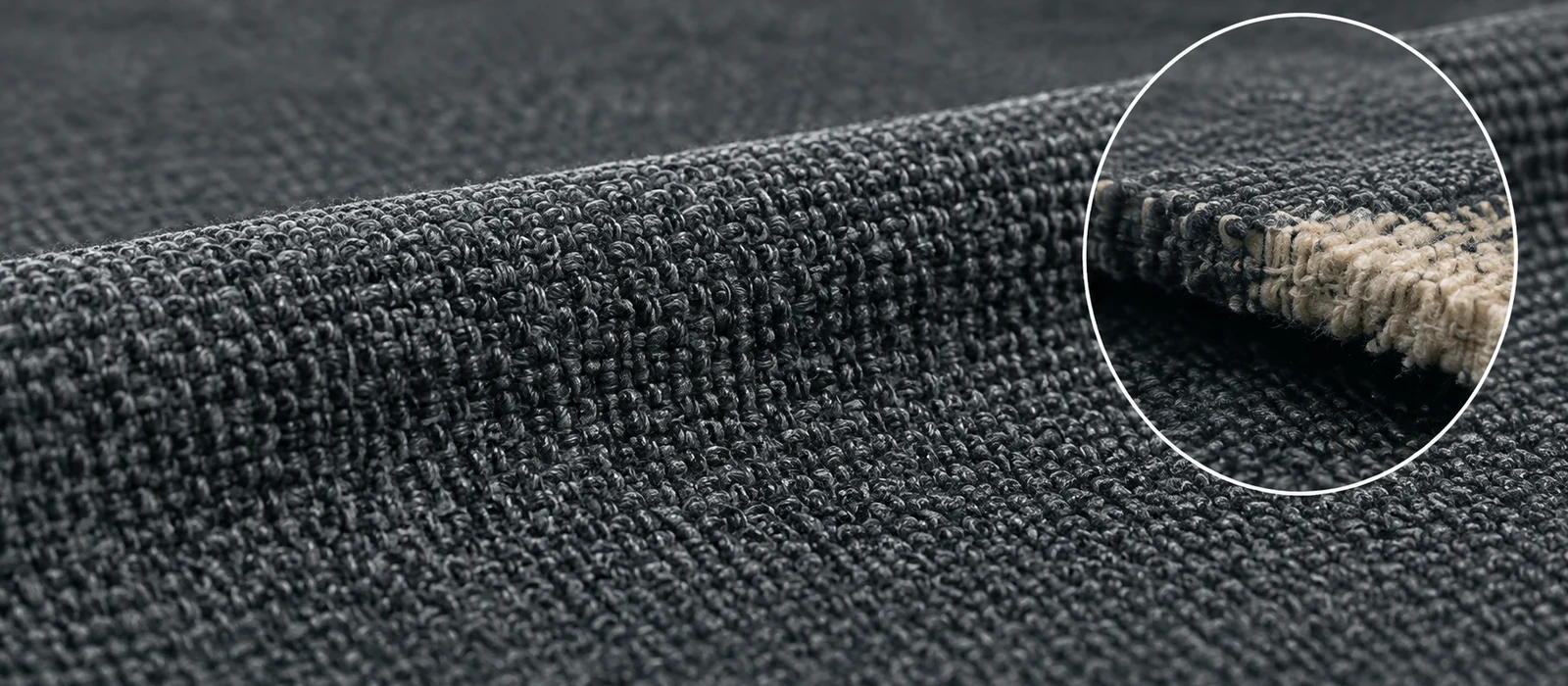 Piece-dyed charcoal performance fabric, magnified on the cut edge where the yarn core is still pale and undyed