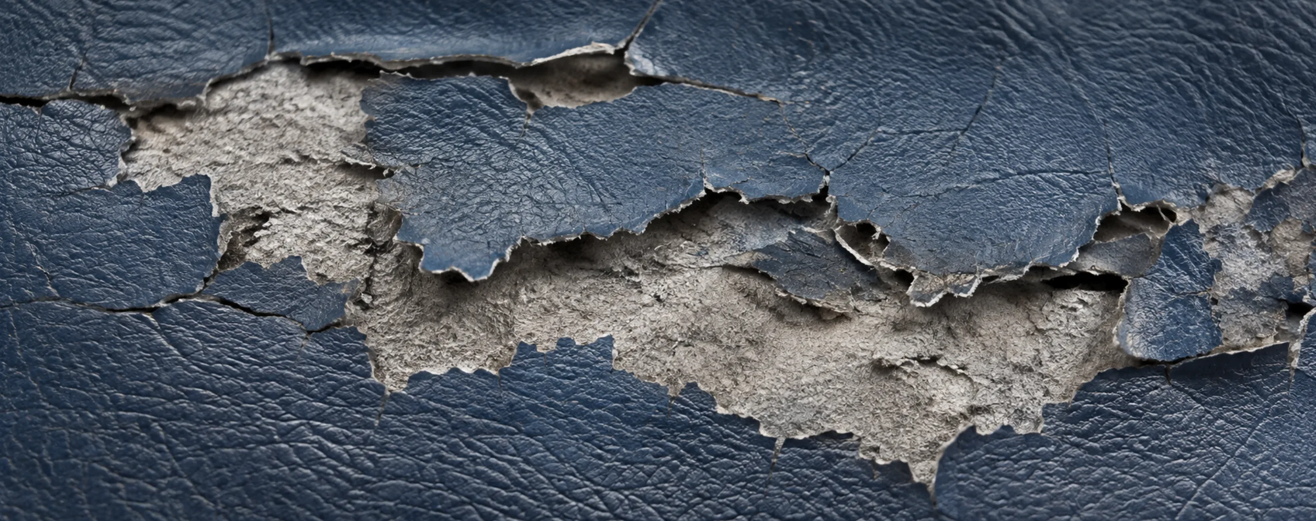 Navy PU faux leather lifting and peeling off its backing in a jagged band