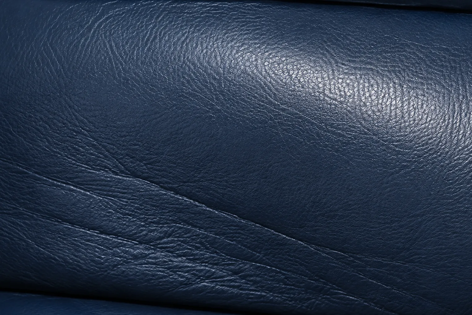 Soft creases forming across a navy PU faux leather cushion as the polymer degrades