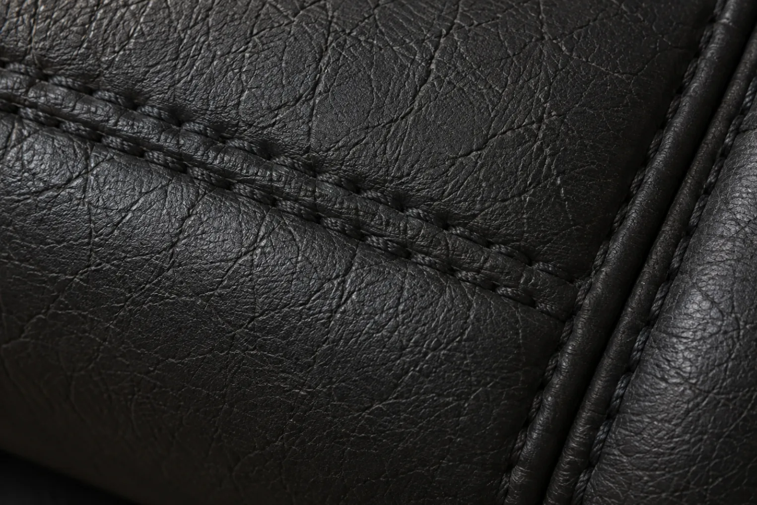 Stitched seam lines on black PVC vinyl, where hardened faux leather cracks first