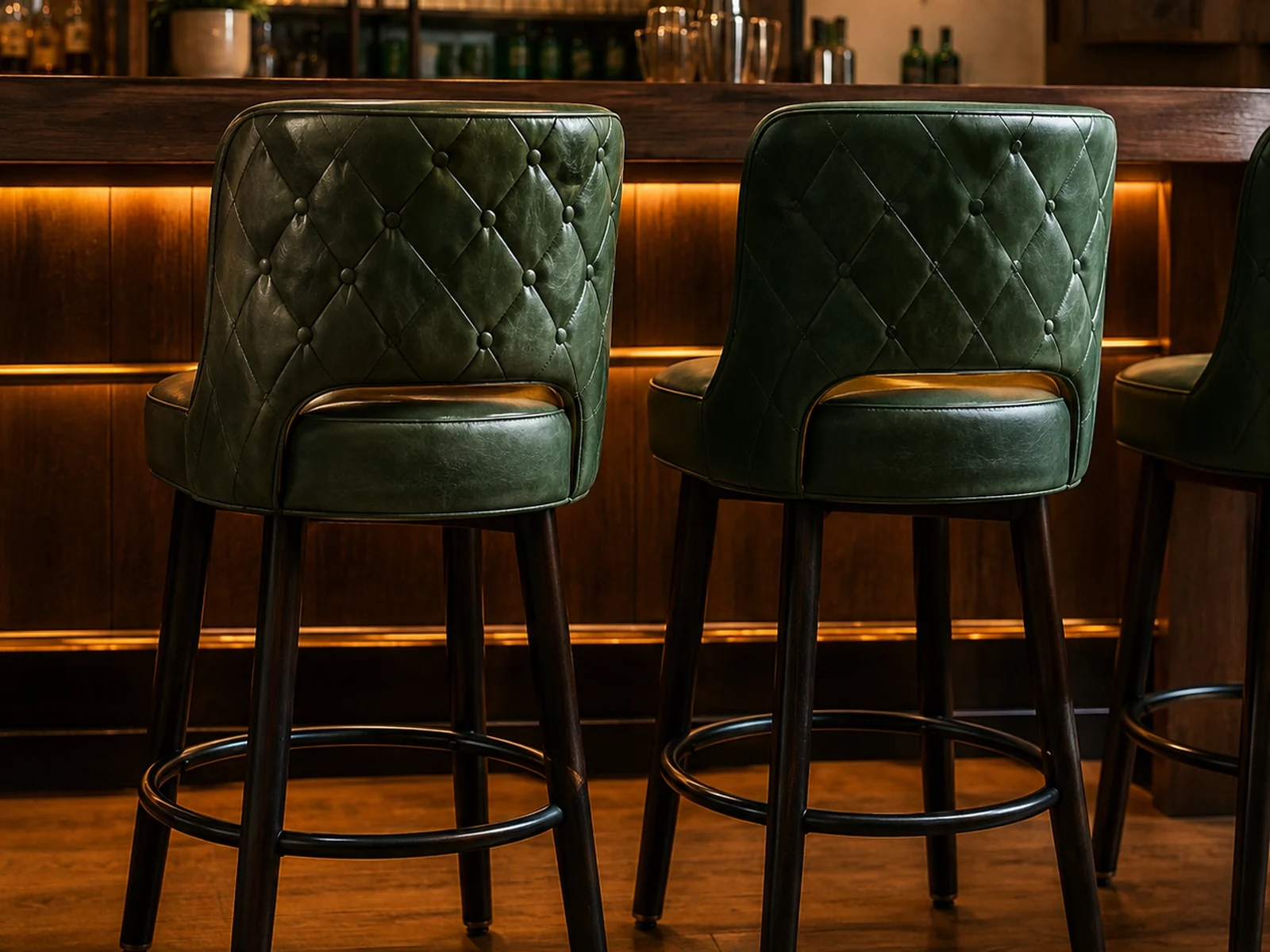 Green quilted leather bar stools reupholstered at a restaurant bar counter