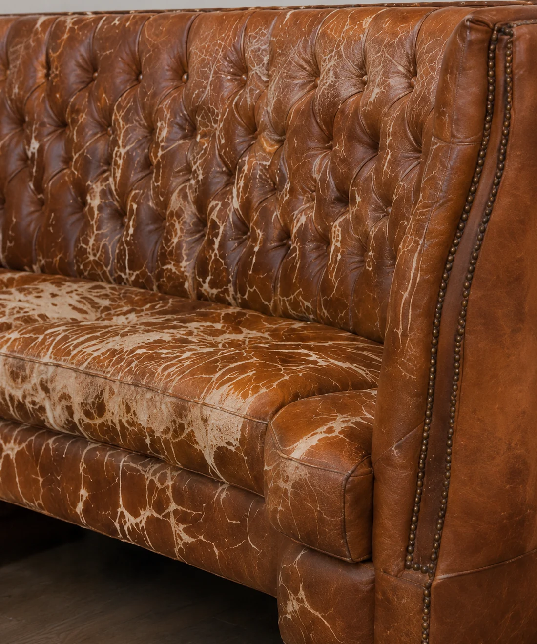 Restaurant chesterfield banquette before reupholstery, the leather cracked and flaking across the seat and buttoned back