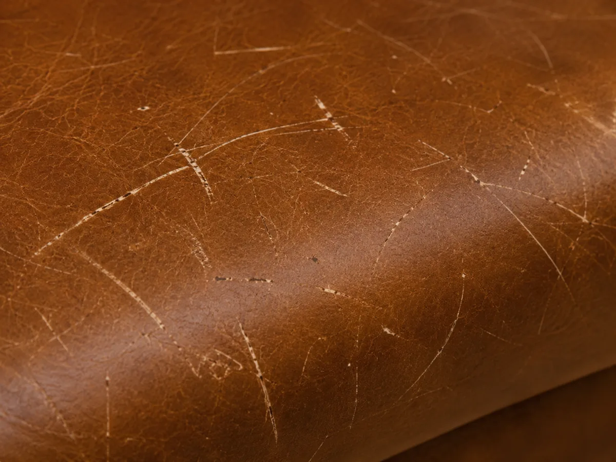 Scratches and scuffs across a brown leather restaurant seat panel