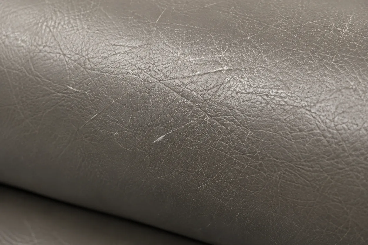 A grey leather seat roll gone dry and flat, its sheen scratched away