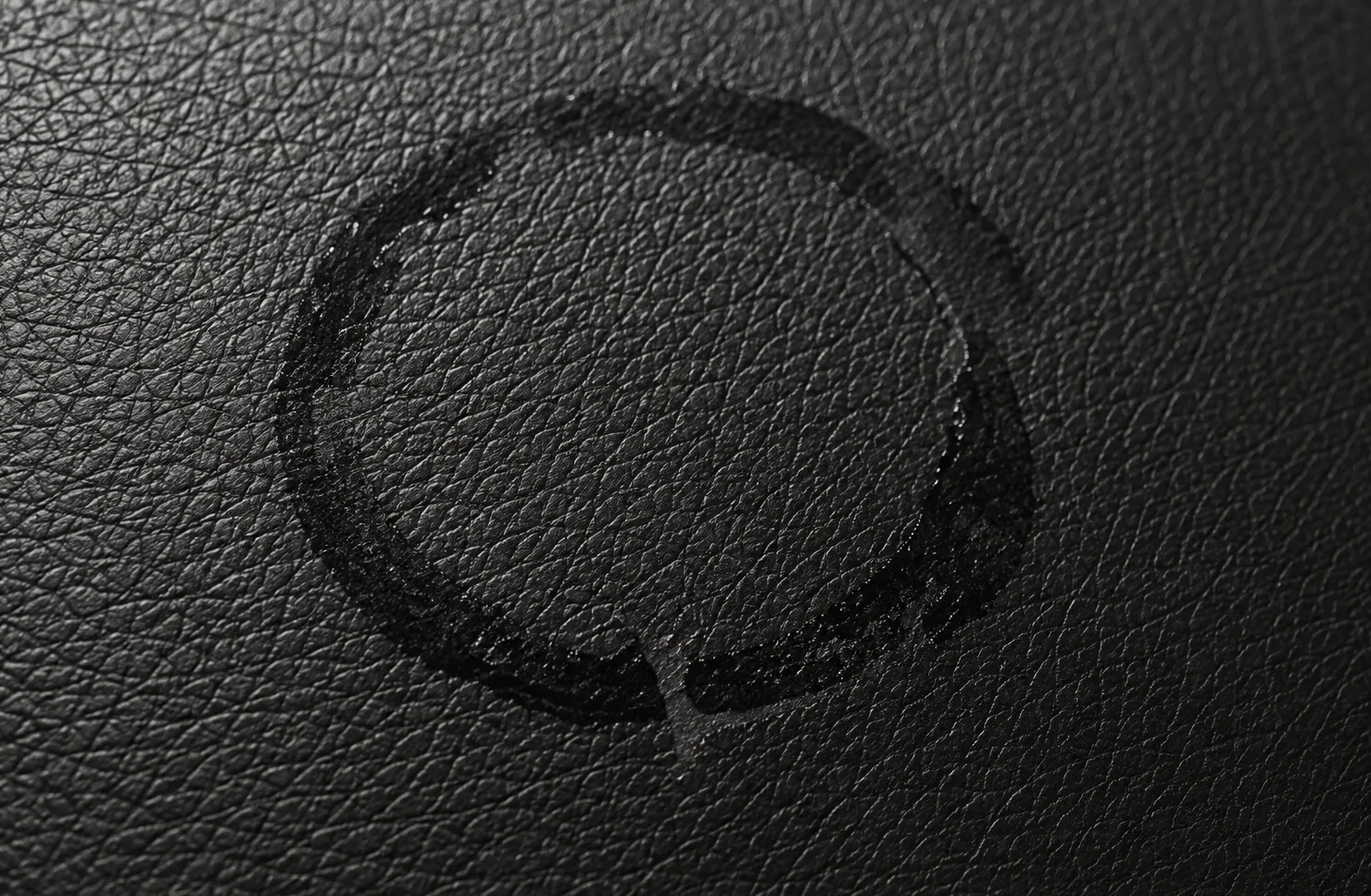 Glossy circular glass ring marks left on black bar seating leather