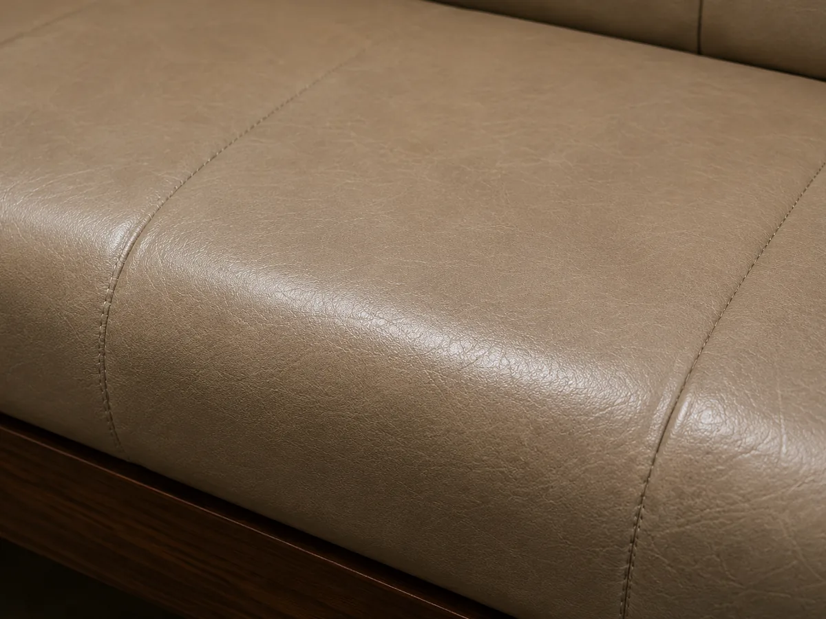 A taupe leather bench seat with the topcoat cured, the sheen even across the panel and its stitched seams