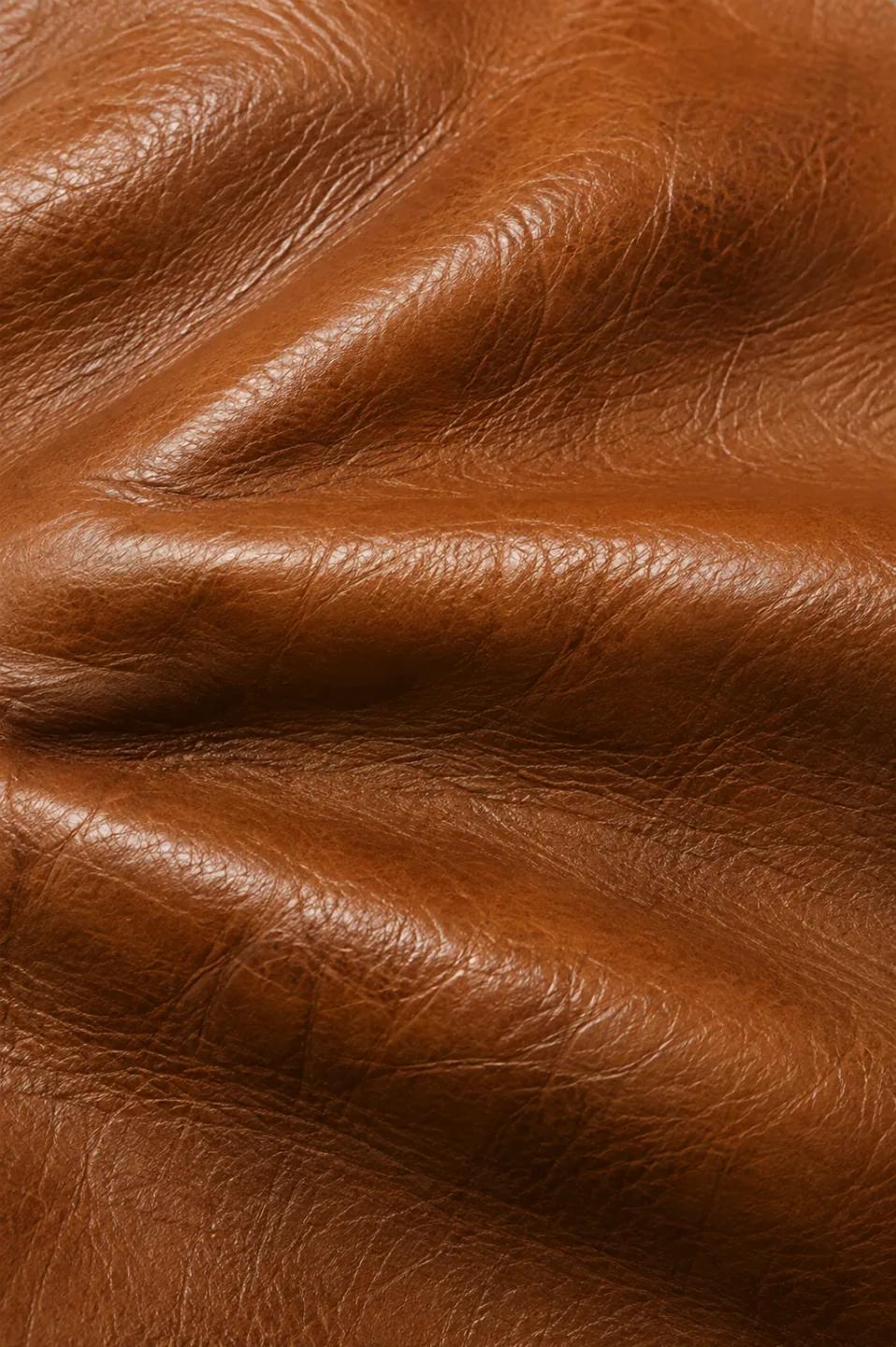 Aniline leather sofa being restored, with translucent color rebalanced across the seat panels and the grain still visible